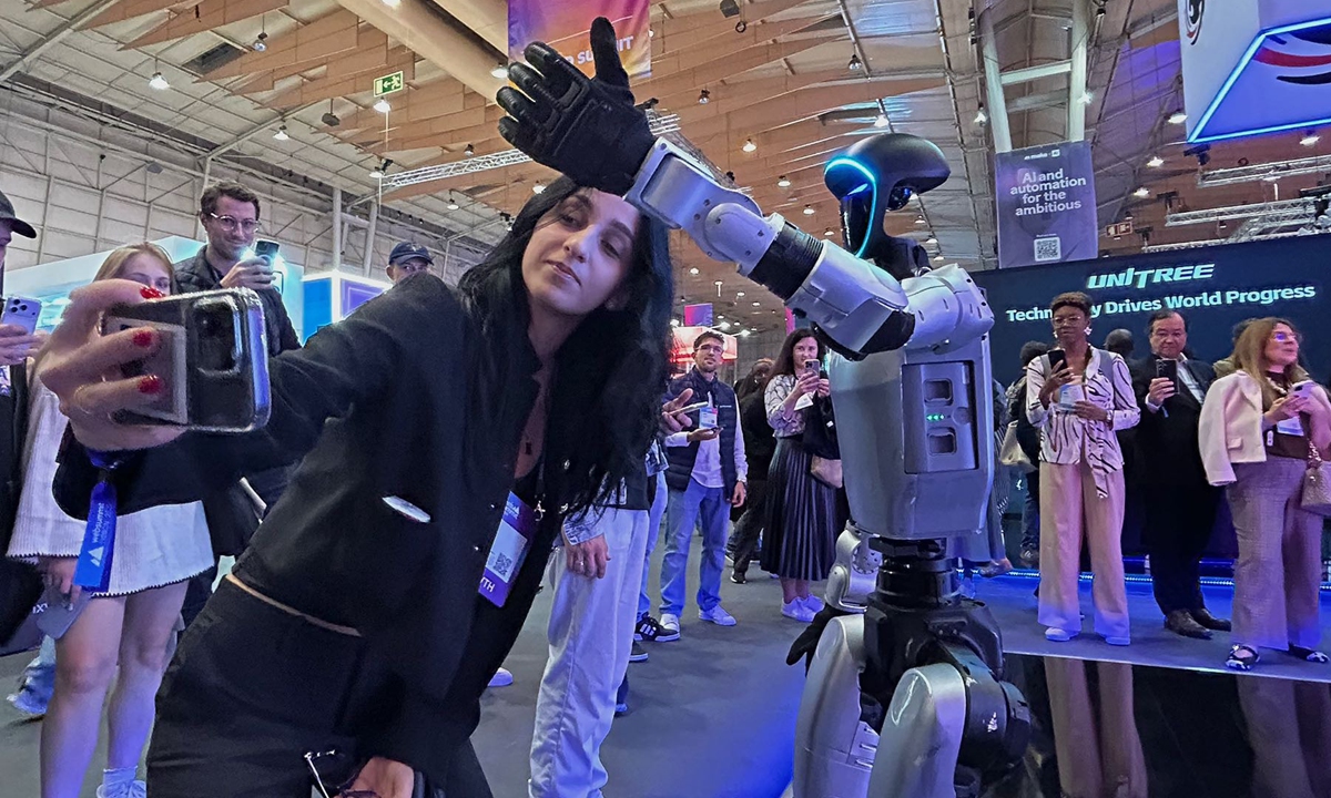 A visitor takes a photo with a humanoid robot developed by China's Unitree Robotics during the Web Summit annual tech conference held in Lisbon, Portugal, on November 11, 2025. Photo: VCG