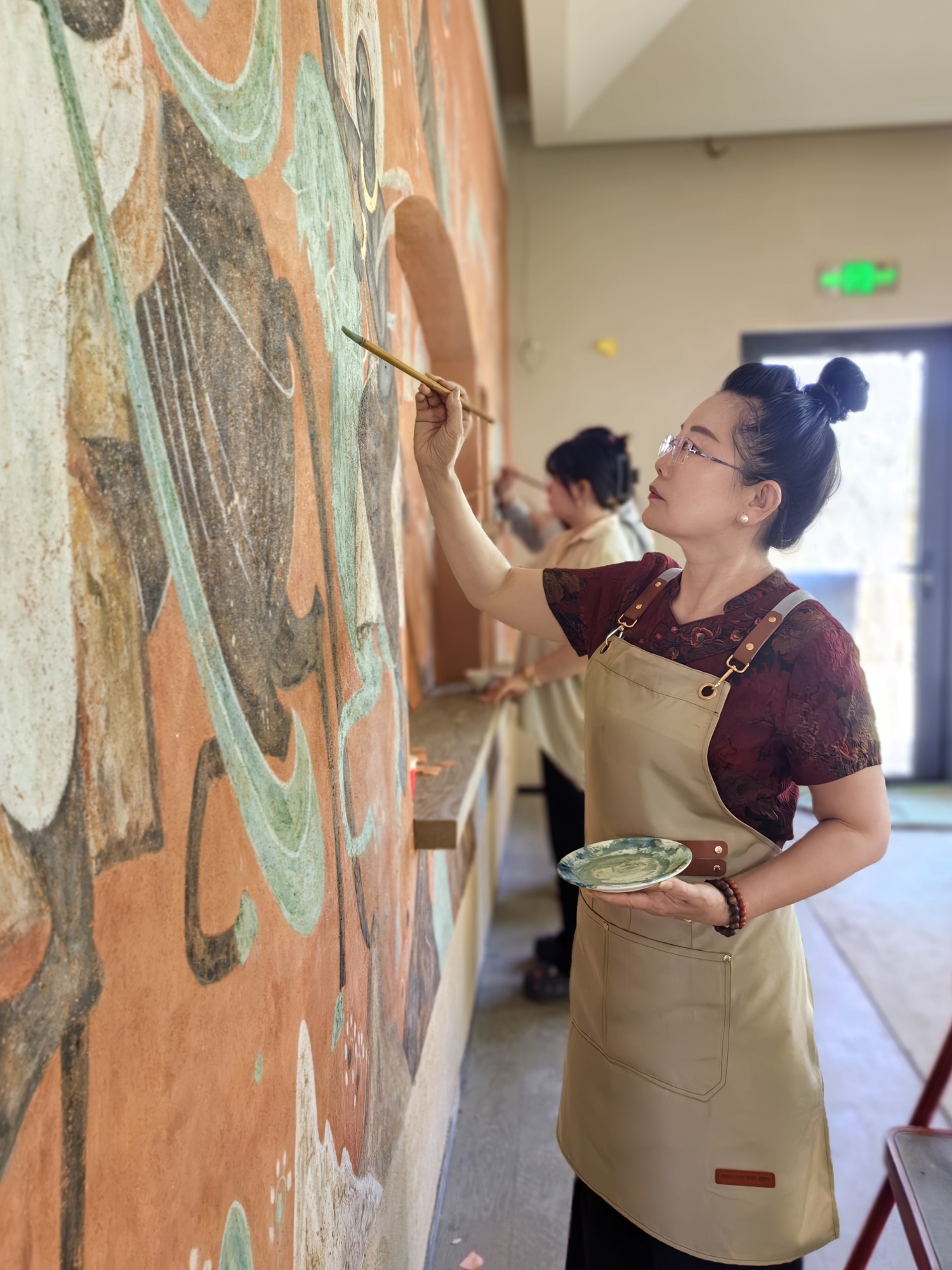 Wang Yalin, a fourth-generation inheritor of the Dunhuang stone-powder painting technique, reproduces the Feitian murals of Dunhuang. Photo: Courtesy of Wang Yalin