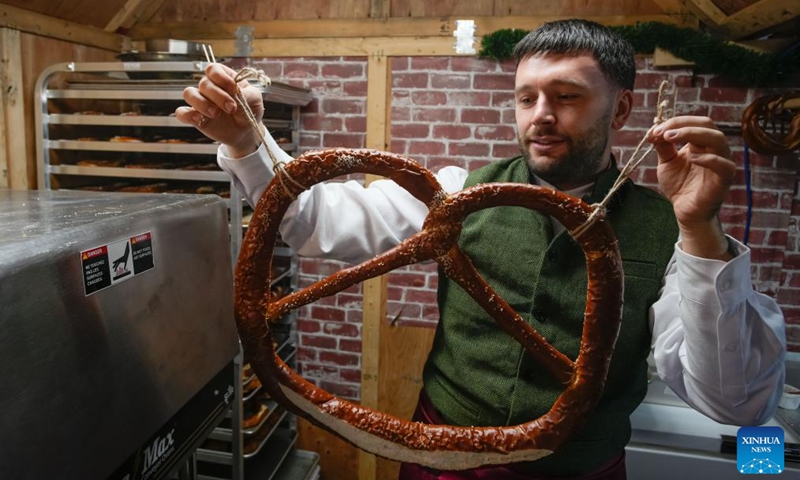 A vendor shows a large pretzel in a wooden hut at the Vancouver Christmas Market in Vancouver, British Columbia, Canada, Nov. 14, 2025. The annual festive event features more than 110 wooden huts offering various handicrafts, traditional European food, drink, and souvenirs, along with live performances. This year's market opened here on Thursday and will run until Dec. 24. Photo: Xinhua