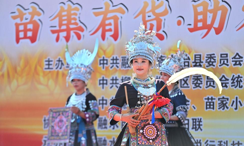 Actresses display embroideries of Miao ethnic group and lusheng, a traditional reed-pipe wind instrument, at an agricultural fair in Rongshui Miao Autonomous County, south China's Guangxi Zhuang Autonomous Region, Nov. 15, 2025. A Miao town community of Rongshui County held this fair to showcase and promote agricultural specialties and intangible cultural heritage from neighboring townships. Photo: Xinhua