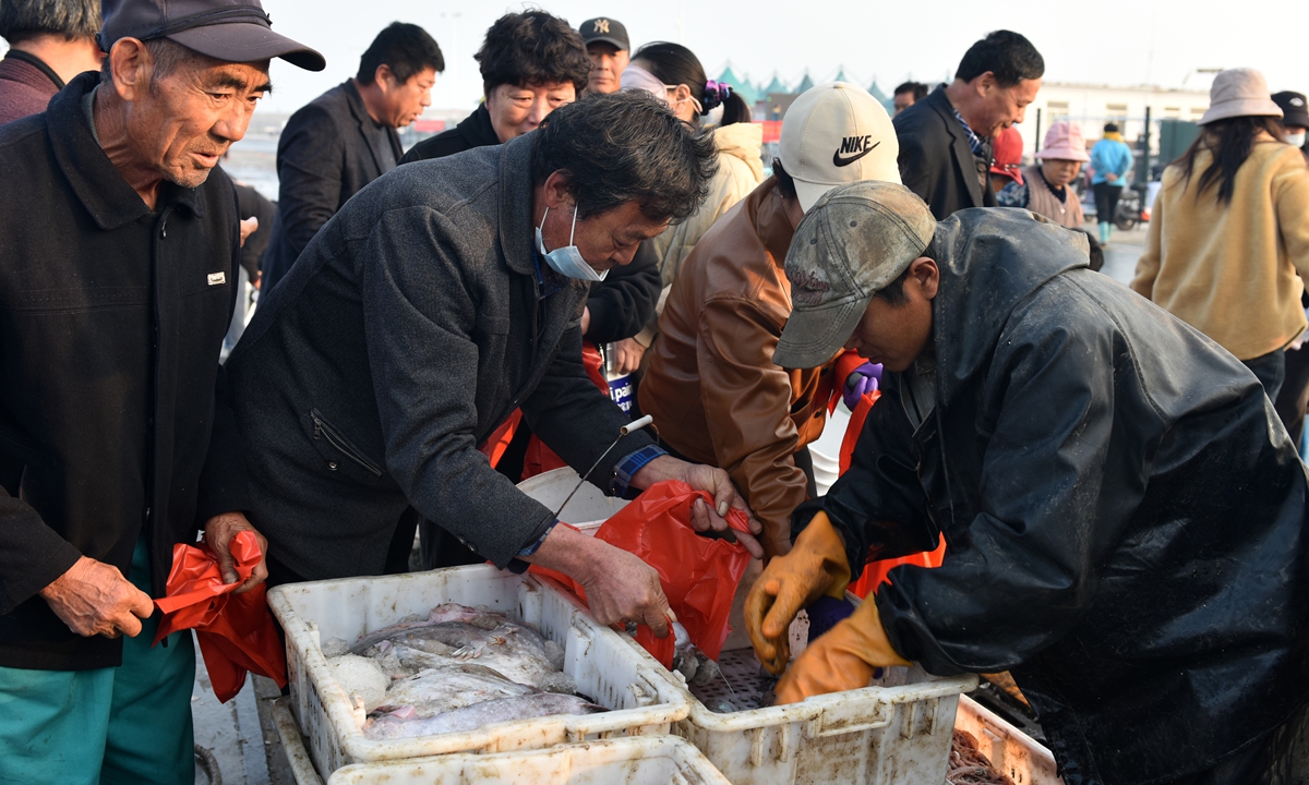 Locals and tourists eagerly snap up seafood at a fishing port in Rizhao, East China's Shandong Province on November 16, 2025. On the same day, fishing boats returned to port due to strong winds and dropping temperatures, bringing back freshly caught seafood. Photo: VCG