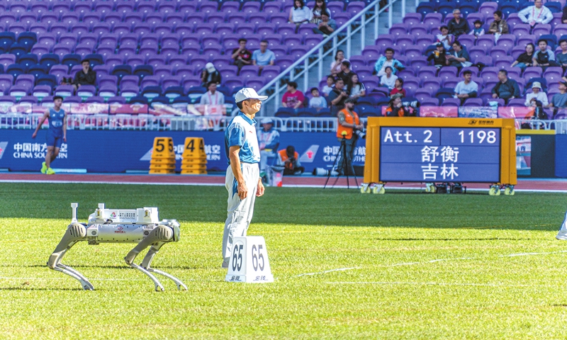 A robot dog and a volunteer stand on the track and field venue of China's 15th National Games in Guangzhou, South China's Guangdong Province on November 17, 2025. Photo: VCG