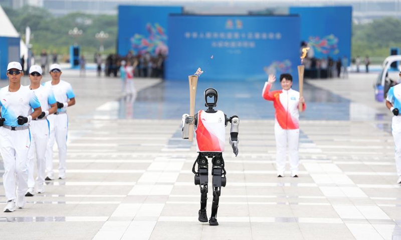 Torchbearer humanoid robot Kuavo (front) runs during the torch relay for China's 15th National Games in Shenzhen, on Nov. 2, 2025. (Xinhua/Jiang Han)