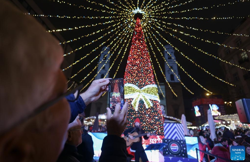 A visitor takes photos of a Christmas tree at a Christmas market in downtown Budapest, Hungary, on Nov. 15, 2025. The market opened here on Friday and will last till Jan. 1, 2026. (Photo by Attila Volgyi/Xinhua)