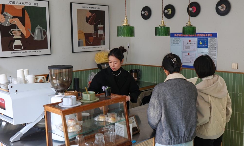 Gao Qingying (L), a cafe owner who has returned from Shanghai to start a business at home, serves customers in Dongluo Village of Xinghua, east China's Jiangsu Province, Nov. 21, 2025. Local authorities in Xinghua have sought to embed environmental construction into the rural industry landscape in recent years, helping create numerous villages that are both livable and suitable for business operations. Photo: Xinhua