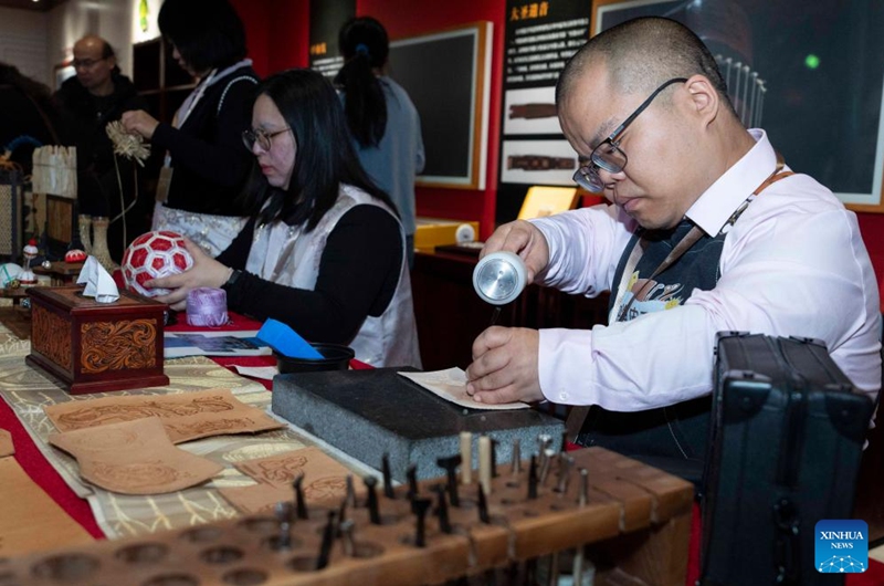 A disabled artist (R) demonstrates leather carving skills during an exhibition held at the Sensory Experience Gallery of the Palace Museum in Beijing, capital of China, Nov. 21, 2025. Featuring artworks created by disabled artists from Shanghai, the exhibition kicked off here on Friday. Under the guidance of inheritors of intangible cultural heritages, these artists infused their love for life and reverence for culture into their works. Photo: Xinhua