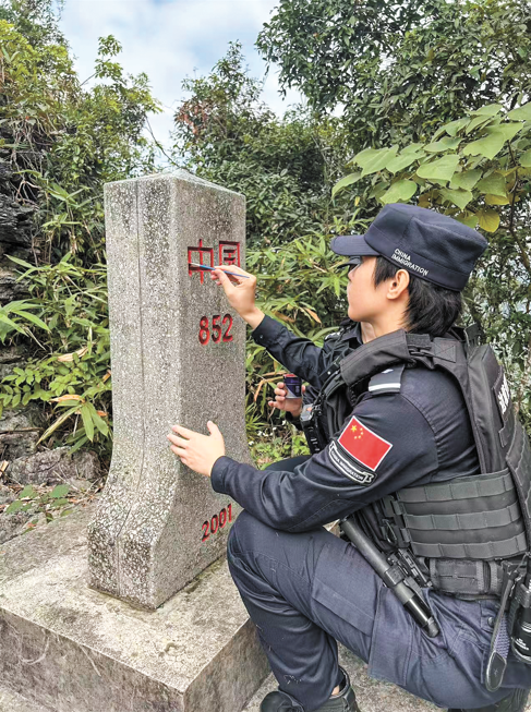 Yang Huan, caption of the Detian women police pioneer team, touches up a border monument with red paint in Chongzuo, Southwest China's Guangxi Zhuang Autonomous Region. Photo: Huang Lanlan/GT