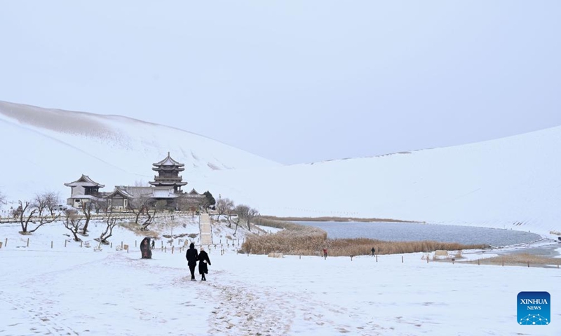 Tourists visit the Mingsha Mountain and Crescent Spring Scenic Area in Dunhuang City, northwest China's Gansu Province, on Nov. 23, 2025. Covered in a blanket of snow, the well-known tourist attractions in Dunhuang presented a stunning winter landscape. (Photo by Zhang Xiaoliang/Xinhua)