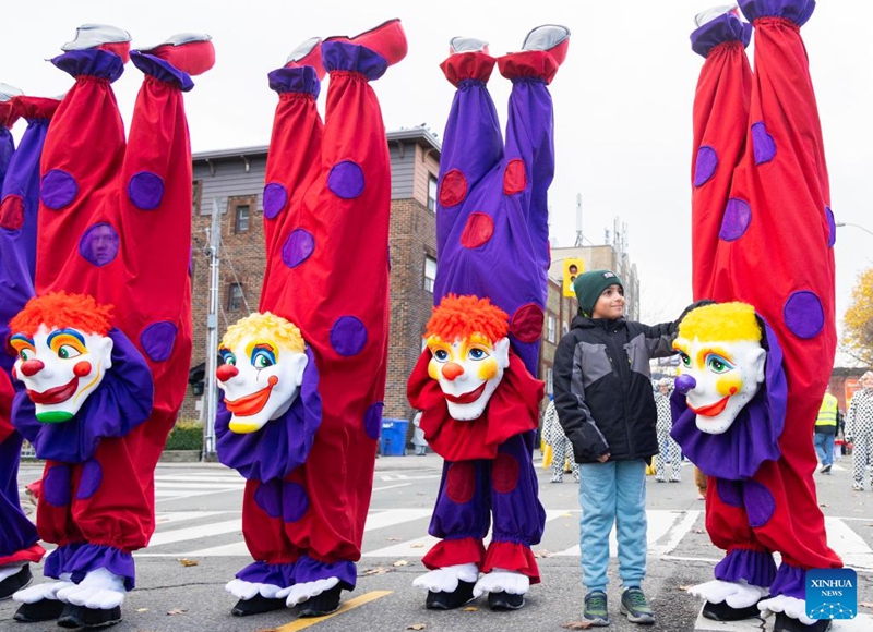 A boy poses for photos with dressed-up paraders during the 2025 Original Santa Claus Parade in Toronto, Canada, on Nov. 23, 2025. Featuring dozens of themed floats and marching bands, the annual parade was held here on Sunday. (Photo by Zou Zheng/Xinhua)