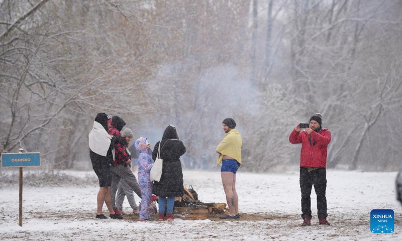 Winter swimmers warm up by a bonfire on the snowy banks of the Vistula River in Warsaw, Poland, on Nov. 23, 2025. Sunday marked the opening of the cold-water swimming season in Warsaw. (Photo by Jaap Arriens/Xinhua)