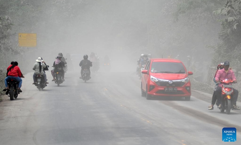 People ride vehicles amid smoke and ash erupted from the Semeru volcano at Sumberwuluh village in Lumajang regency, East Java, Indonesia, Nov. 23, 2025. Indonesia's Semeru volcano erupted on Wednesday, prompting the country's volcanology agency to raise the alert level to the maximum. (Photo by Sahlan Kurniawan/Xinhua)