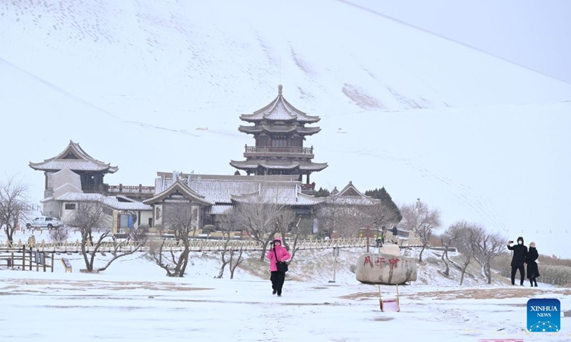 Tourists visit the Mingsha Mountain and Crescent Spring Scenic Area in Dunhuang City, northwest China's Gansu Province, on Nov. 23, 2025. Covered in a blanket of snow, the well-known tourist attractions in Dunhuang presented a stunning winter landscape. (Photo by Zhang Xiaoliang/Xinhua)