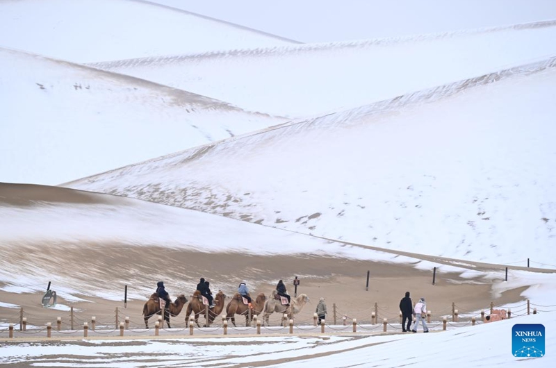 Tourists visit the Mingsha Mountain and Crescent Spring Scenic Area in Dunhuang City, northwest China's Gansu Province, on Nov. 23, 2025. Covered in a blanket of snow, the well-known tourist attractions in Dunhuang presented a stunning winter landscape. (Photo by Zhang Xiaoliang/Xinhua)