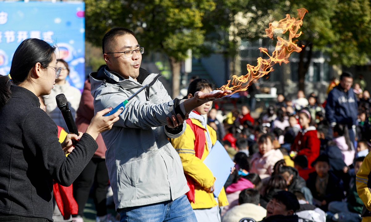A teacher at a local school in Sihong, East China's Jiangsu Province, demonstrates to students a chemical experiment using combustion principles to create the visual effect of a burning palm on November 25, 2025. The school's science and technology festival kicked off earlier that day. Photo: VCG