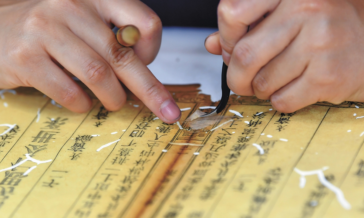 An ancient book restorer inspects the repaired pages of a manuscript. Photo: VCG