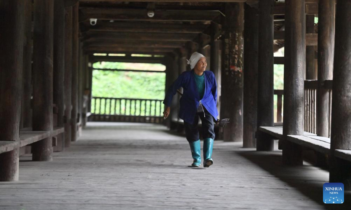 An old woman walks past a timber lounge bridge in Batuan Village in Sanjiang Dong Autonomous County, south China's Guangxi Zhuang Autonomous Region, Nov. 5, 2025. Mountains, gullies and streams surrounding the villages across Guangxi's rural area make bridges the must for production and daily life. Small bridges are not only important transportation link, but also play a crucial role in culture inheritance, industrial development and rural revitalization. (Xinhua/Huang Xiaobang)