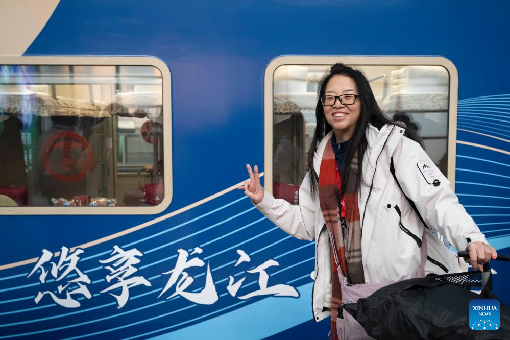 A passenger poses for photos with the Train Y783 on Nov. 26, 2025. Train Y783, an ice-and-snow themed tourism train, was launched at Harbin Railway Station and started a six-day trip on Wednesday. The train showcases the charm of northeastern China through themed decorations, tour guide services and interactive activities, in an effort to promote winter tourism and inject new vitality into ice and snow economy. (Xinhua/Zhang Tao)