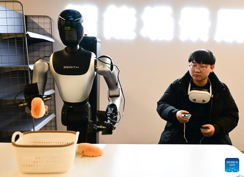 A staff member trains a humanoid robot to fetch objects for data collection purpose at Zerith, a robotics company, in Hefei, east China's Anhui Province, Nov. 25, 2025. In recent years, Hefei has been actively promoting the development of its intelligent robot industry. The city is now home to a full-chain industrial system for research, development and manufacturing of robotics that comprises 190 related enterprises. (Xinhua/Zhou Mu)