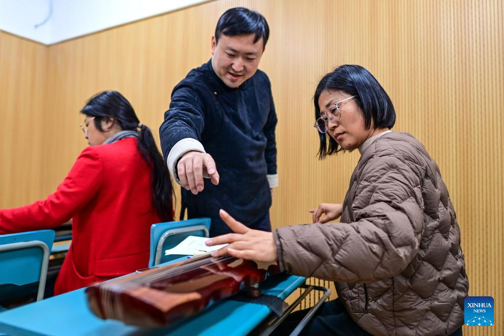 A teacher (C) instructs a citizen to play guqin, a plucked seven-string traditional Chinese musical instrument, during a night-time class held at the youth activity center in Jiangbei District of Ningbo, east China's Zhejiang Province, Nov. 26, 2025. Starting from 2024, Jiangbei District in Ningbo has integrated educational and training resources from universities, hospitals, law firms and other enterprises and institutions in a night-time school project, offering courses in foreign languages, dance, music and fashion design, among others. It has enrolled more than 9,600 citizens by now. (Xinhua/Jiang Han)