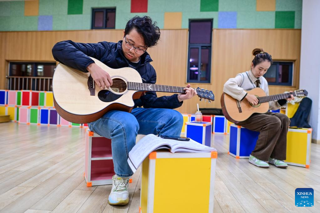 Citizens play guitar during a night-time class held at the youth activity center in Jiangbei District of Ningbo, east China's Zhejiang Province, Nov. 26, 2025. Starting from 2024, Jiangbei District in Ningbo has integrated educational and training resources from universities, hospitals, law firms and other enterprises and institutions in a night-time school project, offering courses in foreign languages, dance, music and fashion design, among others. It has enrolled more than 9,600 citizens by now. (Xinhua/Jiang Han)