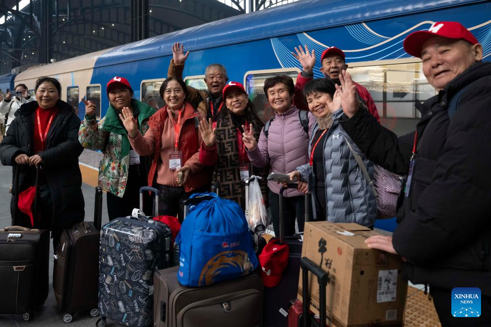 Passengers pose for photos with the Train Y783 on Nov. 26, 2025. Train Y783, an ice-and-snow themed tourism train, was launched at Harbin Railway Station and started a six-day trip on Wednesday. The train showcases the charm of northeastern China through themed decorations, tour guide services and interactive activities, in an effort to promote winter tourism and inject new vitality into ice and snow economy. (Xinhua/Zhang Tao)