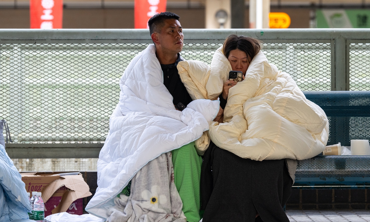 Residents rest near the fire scene in the Tai Po district of Hong Kong's New Territories, on November 27, 2025. Photo: VCG
