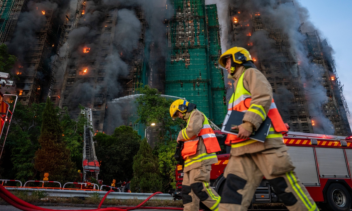 Fire firefighters walk pass smoke and flames at the fire scene in the Tai Po district of Hong Kong's New Territories on November 27 2025.  Photo: VCG