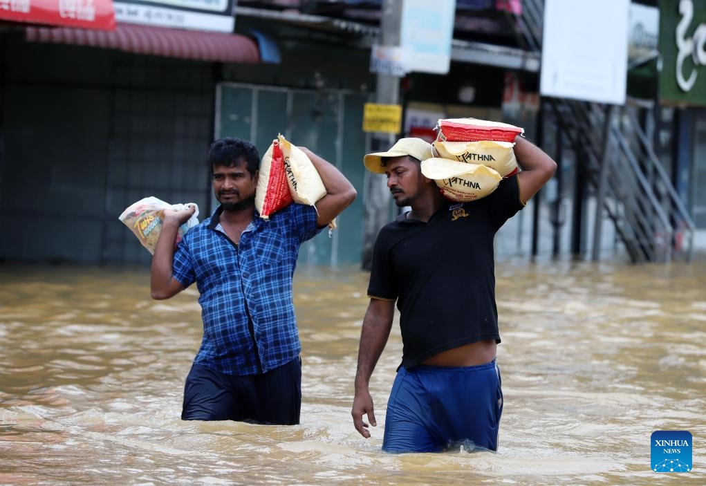 People transfer goods in floodwater after heavy rains on the outskirts of Colombo, Sri Lanka, on Nov. 29, 2025. Sri Lankan President Anura Kumara Dissanayake has declared a State of Public Emergency effective on Friday, as the country confronts one of its worst weather-related disasters in recent years. (Photo by Ajith Perera/Xinhua)