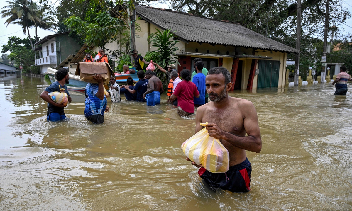 Residents carrying belongings wade through a flooded area after heavy rainfall from Cyclone Ditwah in Wellampitiya on the outskirts of Colombo, Sri Lanka on December 1, 2025. At least 340 people have been killed in the country with many more still missing, officials said. Photo: VCG