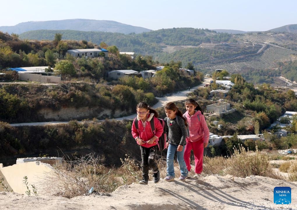 Girls walk up a hillside path overlooking the makeshift displacement camps in Khirbet al-Joz of northwestern Idlib province, Syria, Nov. 20, 2025. (Str/Xinhua)