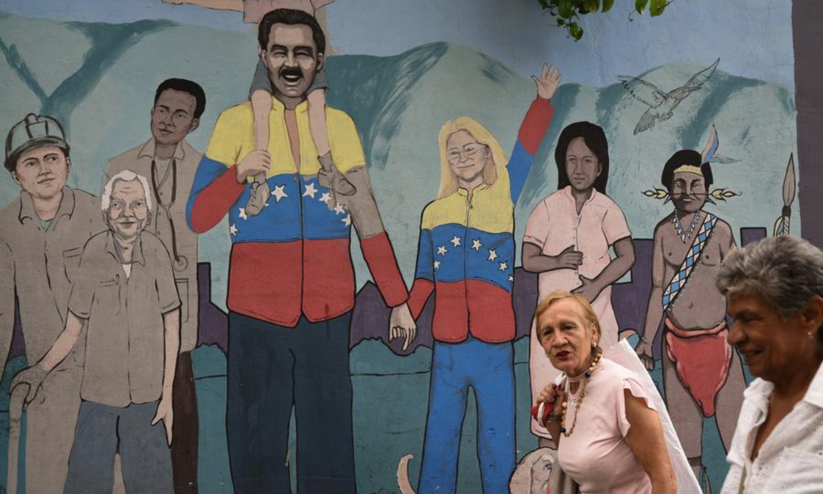 People walks past a mural in Caracas, Venezuela, Nov. 5, 2025. Venezuelan President Nicolas Maduro has repeatedly condemned Washington's actions as attempts to overthrow his government and expand the U.S. military influence in Latin America. (Photo by Marcos Salgado/Xinhua)