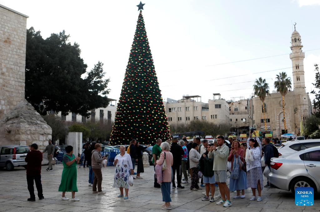 Tourists visit the main Christmas tree in Manger Square in Bethlehem in the West Bank, Dec. 1, 2025. With Christmas nearing, Manger Square and the Church of the Nativity are welcoming more international visitors, bringing hope for a strong and festive season. (Photo by Mamoun Wazwaz/Xinhua)