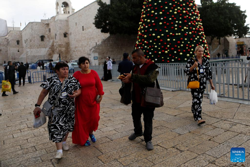 Tourists walk around the main Christmas tree in Manger Square in Bethlehem in the West Bank, Dec. 1, 2025. With Christmas nearing, Manger Square and the Church of the Nativity are welcoming more international visitors, bringing hope for a strong and festive season. (Photo by Mamoun Wazwaz/Xinhua)