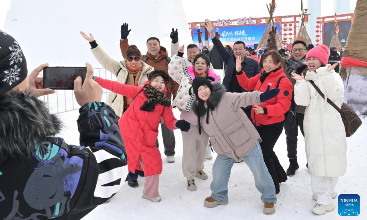 Tourists pose for photos during an ice collecting festival in Harbin, northeast China's Heilongjiang Province, Dec. 7, 2025. Marking the beginning of Harbin's ice collecting season, the sixth ice collecting festival kicked off here by the Songhua River on Sunday, attracting lots of people with ice collecting ceremony and folk custom experience activities. (Photo by Yuan Yong/Xinhua)