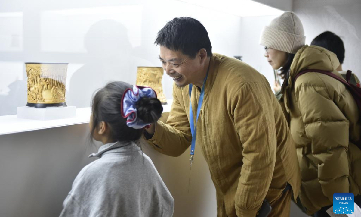 Hong Jianhua (2nd L) introduces his works displayed during an exhibition titled 