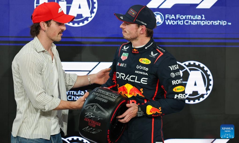 Red Bull's Dutch Driver Max Verstappen (R) receives the pole position award from American singer Benson Boone after the Qualifying of Formula One Abu Dhabi Grand Prix at the Yas Marina Circuit in Abu Dhabi, the United Arab Emirates, on Dec. 6, 2025. (Photo by Qian Jun/Xinhua)