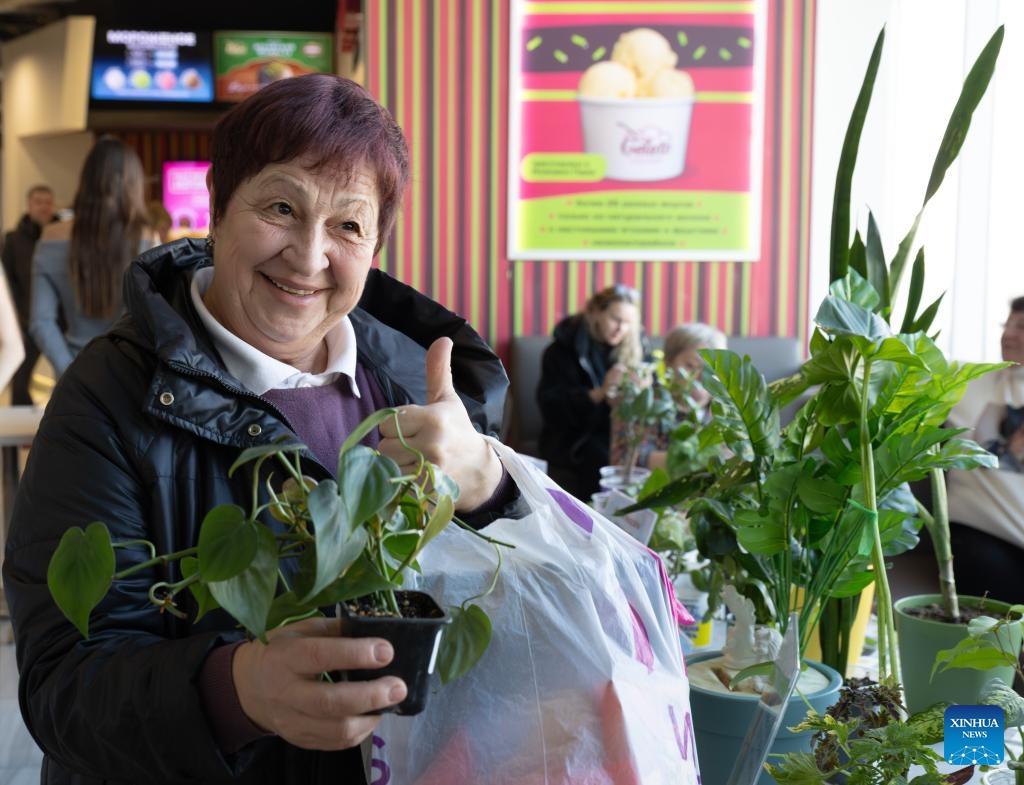 A woman poses for a photo with a potted plant at a plant and flower market in Vladivostok, Russia, Dec. 7, 2025. (Photo by Andrey Matveenko/Xinhua)