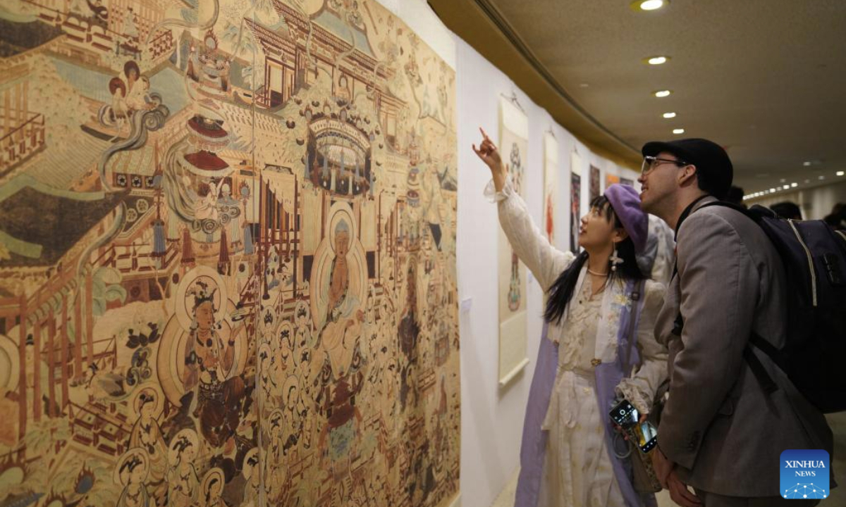 People visit an exhibition showcasing Tsinghua University's research and design work inspired by the ancient art of Dunhuang at the UN headquarters in New York, Dec. 8, 2025. More than 80 works are on display at the exhibition, from early masters such as Pang Xunqin, Chang Sha'na, Chen Hanmin and Liu Jude, to new pieces by Tsinghua students and alumni. (Xinhua/Zhang Fengguo)