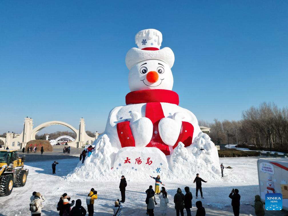A drone photo taken on Dec. 9, 2025 shows tourists taking photos in front of Mr. Snowman at the Sun Island scenic spot in Harbin, northeast China's Heilongjiang Province. Mr. Snowman, an iconic snow sculpture landscape of the 38th Sun Island International Snow Sculpture Art Expo with a height of 23.8 meters and made with 5,000 cubic meters of snow, was officially unveiled at the Sun Island scenic spot on Tuesday. (Photo by Liu Yang/Xinhua)