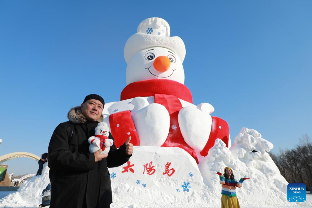 Tourists pose for photos in front of Mr. Snowman at the Sun Island scenic spot in Harbin, northeast China's Heilongjiang Province, Dec. 9, 2025. Mr. Snowman, an iconic snow sculpture landscape of the 38th Sun Island International Snow Sculpture Art Expo with a height of 23.8 meters and made with 5,000 cubic meters of snow, was officially unveiled at the Sun Island scenic spot on Tuesday. (Photo by Wang Dong/Xinhua)