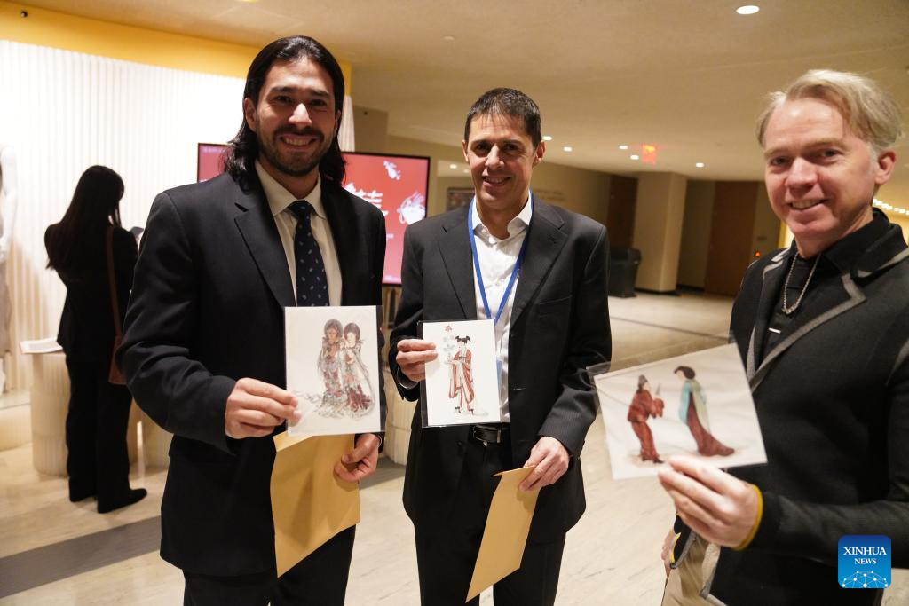 Visitors present cards with Dunhuang elements during an exhibition showcasing Tsinghua University's research and design work inspired by the ancient art of Dunhuang at the UN headquarters in New York, Dec. 8, 2025. More than 80 works are on display at the exhibition, from early masters such as Pang Xunqin, Chang Sha'na, Chen Hanmin and Liu Jude, to new pieces by Tsinghua students and alumni. (Xinhua/Zhang Fengguo)