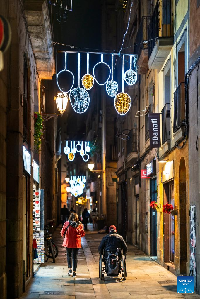 People go down an alley decorated with Christmas lights in Barcelona, Spain, Dec. 10, 2025. (Photo by Joan Gosa/Xinhua)