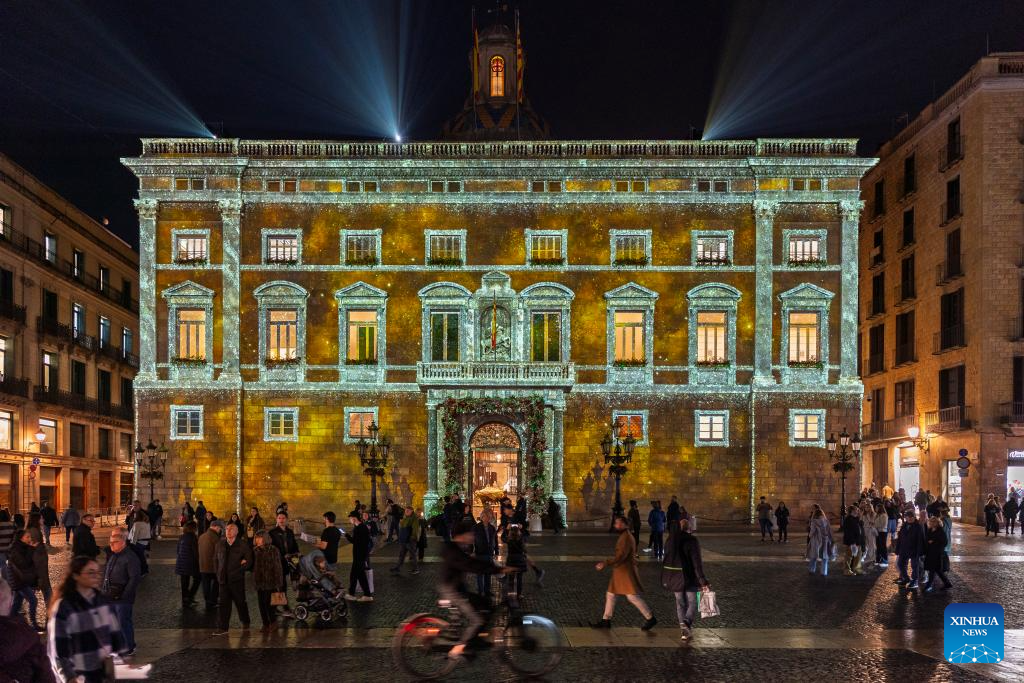 People walk past a building decorated with Christmas lights in Barcelona, Spain, Dec. 10, 2025. (Photo by Joan Gosa/Xinhua)