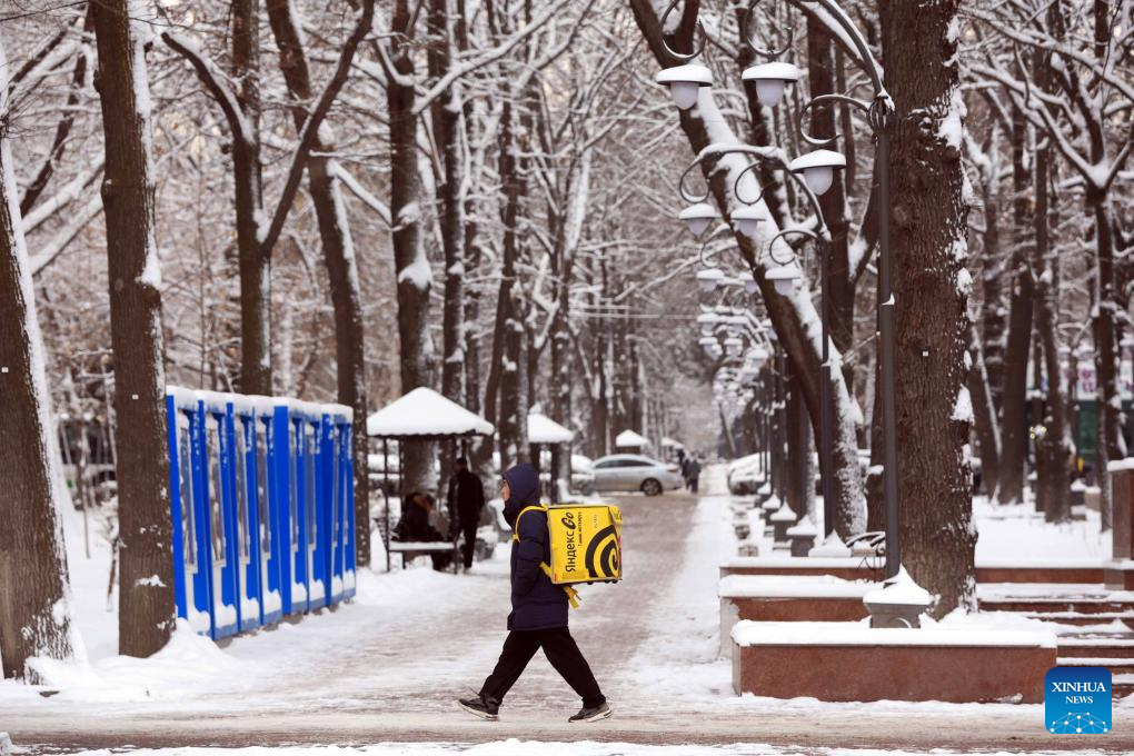 A deliveryman walks in a street after snow in Bishkek, Kyrgyzstan, Dec. 10, 2025. (Photo by Roman/Xinhua)