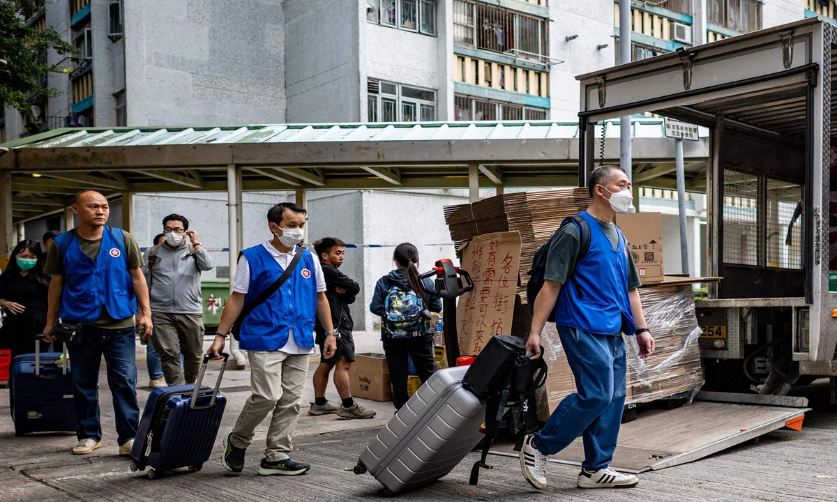 Officials with the Hong Kong Government Quick Response Unit help residents to move their personal belongings from the Wang Fuk Court apartment blocks in the aftermath of the deadly November 26 fire in Hong Kong's Tai Po district on December 3, 2025. Photo: VCG 
