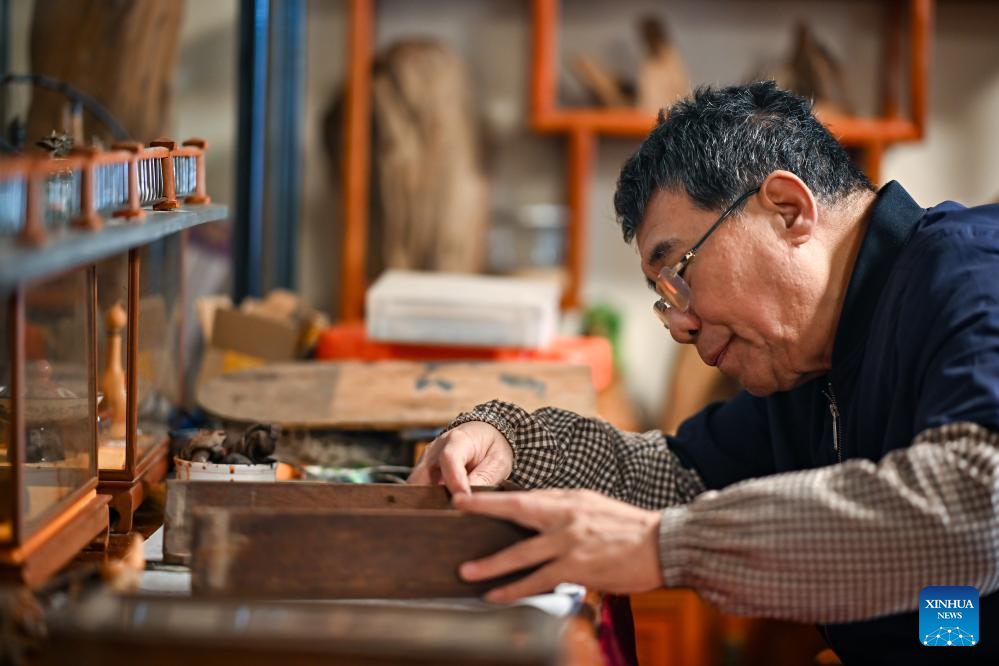 A craftsman repairs a small wooden furniture at a shop in the repair alley in north China's Tianjin, Dec. 9, 2025. A repair alley established in June 2024 has become a lively hub for neighborhood-friendly repair services in Tianjin. In this dedicated zone, local residents have easy access to daily services such as knife sharpening, darning, locksmiths and watch repair. (Xinhua/Zhang Cheng)