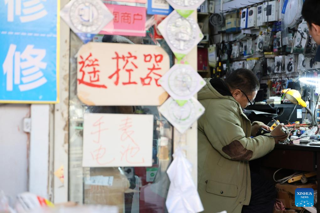 A technician repairs a home appliance at a shop in the repair alley in north China's Tianjin, Dec. 9, 2025. A repair alley established in June 2024 has become a lively hub for neighborhood-friendly repair services in Tianjin. In this dedicated zone, local residents have easy access to daily services such as knife sharpening, darning, locksmiths and watch repair. (Xinhua/Li Ran)