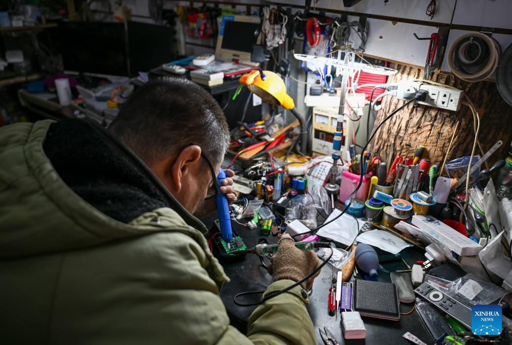 A technician repairs a home appliance at a shop in the repair alley in north China's Tianjin, Dec. 9, 2025. A repair alley established in June 2024 has become a lively hub for neighborhood-friendly repair services in Tianjin. In this dedicated zone, local residents have easy access to daily services such as knife sharpening, darning, locksmiths and watch repair. (Xinhua/Xu Jiayi)