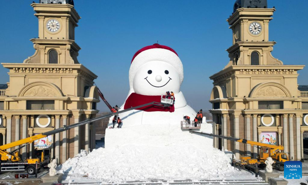 A drone photo shows workers building a giant snowman at the Qunli music park in Harbin, northeast China's Heilongjiang Province, Dec. 14, 2025. This year's giant snowman, 19 meters in height and made with some 3,000 cubic meters of snow, is one meter taller than that of last year. (Photo by Liu Yang/Xinhua)