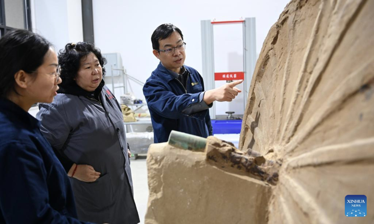 Researchers discuss the cleaning and restoration of a double-shaft chariot unearthed from the Zhaigou site at a laboratory of the Shaanxi Academy of Archaeology in Xi'an, northwest China's Shaanxi Province, Dec. 12, 2025. The Zhaigou site, a settlement site dating back to about 3,200 years ago, was listed as one of the major field archaeological discoveries during the sixth Shanghai Archaeology Forum (SAF2025) in east China's Shanghai on Tuesday. (Xinhua/Li Yibo)